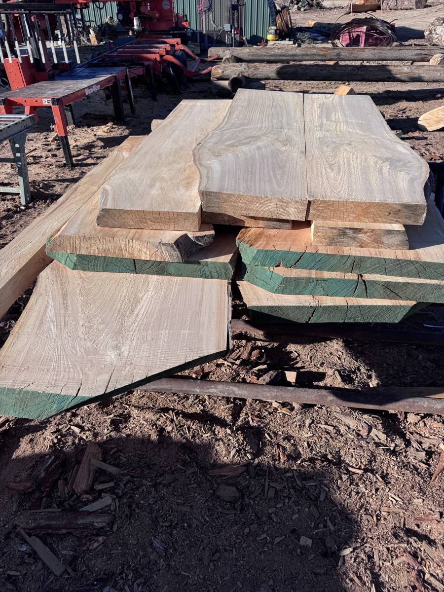 Stack of fresh-cut slabs with sealed ends beside the Wood-Mizer