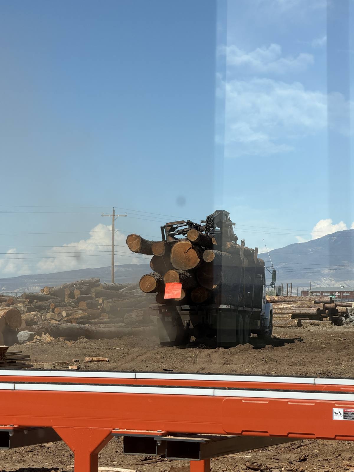 Log truck unloading at the JAMCo yard, seen from the mill