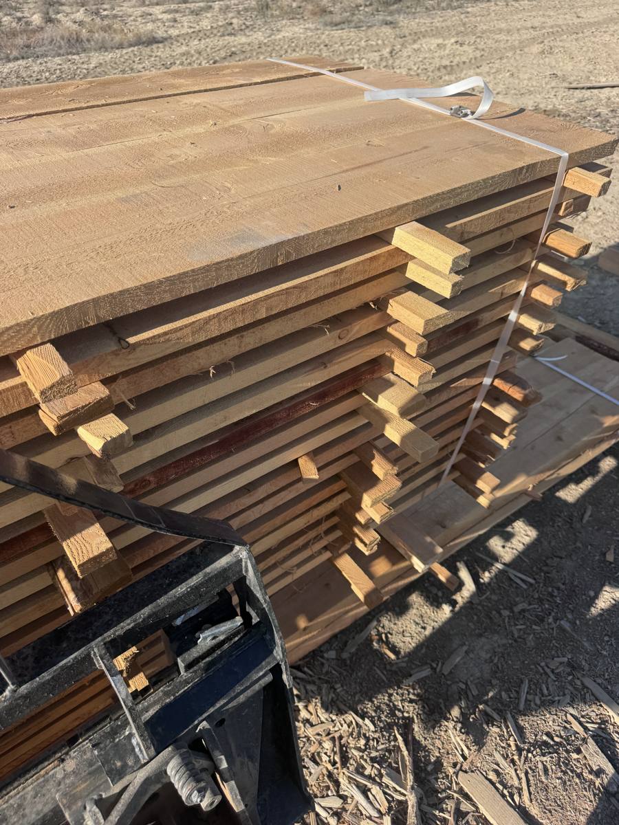 A strapped bundle of rough sawn boards stacked and stickered with spacers between every layer